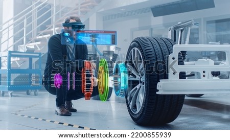 Automotive Engineer Working on Electric Car Chassis Platform, Using Augmented Reality Headset with 3D VFX Software for Development of Regenerative Braking System on a Transport Vehicle. Royalty-Free Stock Photo #2200855939
