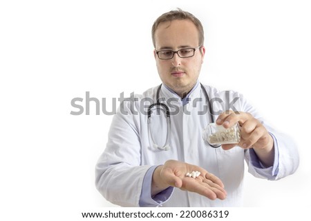 Young Doctor with laboratory coat and stethoscope pouring pills out of a bottle into his hand isolated on white background