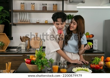 The lovely couple taking their weekend time in the kitchen to prepare their food. The wife feed the apple to her husband.