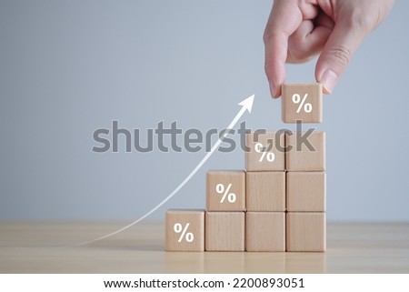 Interest rate finance and mortgage rates. hand holding wooden block with percentage sign and rise of arrow up, financial growth, interest rate increase, inflation, sale price and tax rise concept. Royalty-Free Stock Photo #2200893051