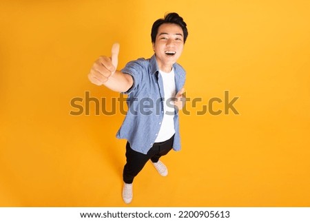 image of asian man posing on a yellow background Royalty-Free Stock Photo #2200905613