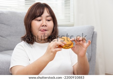 Chubby Asian Woman Licking Her Lip While Enjoy Eating Cheese Burger Royalty-Free Stock Photo #2200910883