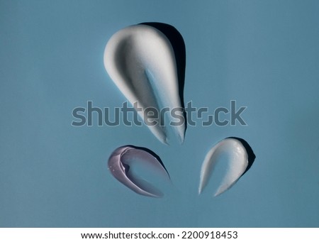 Cosmetic masks of creamy texture on a blue background.