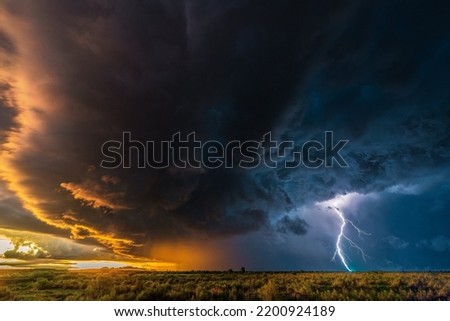 An impressive natural picture of a thundercloud with thunderbolts over a wide field Royalty-Free Stock Photo #2200924189