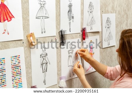 	
The fashion designer develops sketches of clothing design. The artist creates women's dresses. Tailor working with fabric.