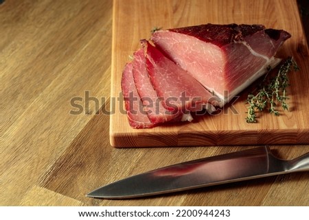 Dry-cured pork fillet with thyme on a wooden cutting board.