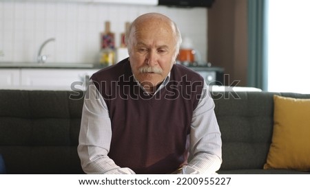 Worried, pensive, 80s old man sitting at home alone, thinking about life alone. Depressed pensive old man with health problems in old age feels lonely. Old age diseases, healthcare concept. Royalty-Free Stock Photo #2200955227