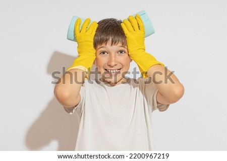 A boy in rubber gloves puts two rolls of toilet paper to his head and smiles. Shows the sign of the ears. Easter bunny concept.