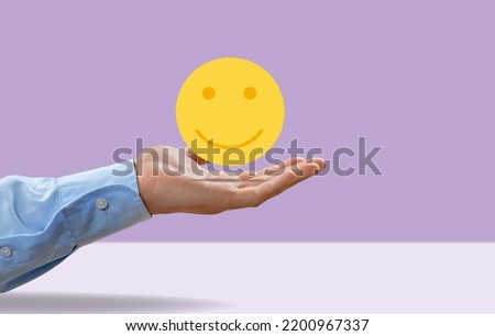 Enjoying Concept. Hand Holding a Smiling Face icon. Sign happy lifestyles.