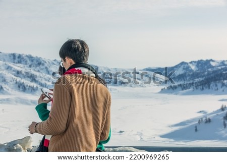 Shot of a young man taking pictures from Sunset over winter snow fields in Altay Prefecture, Xinjiang, China