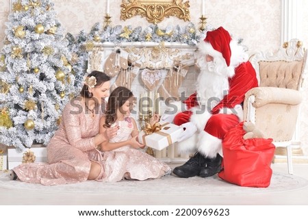 Santa Claus in a traditional costume with his daughter and granddaughter in a room with New Year's decor
