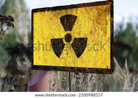 Old textural Sign of radiation hazard against the background of infected nature and forest. Concept: restricted area for visiting, increased background radiation.