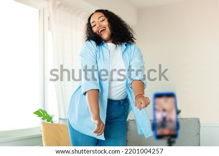 Modern Blogging. Happy Black Female Blogger Making Video On Smartphone Dancing Posing At Home, Selective Focus. Overweight Woman Filming For Personal Social Media Blog