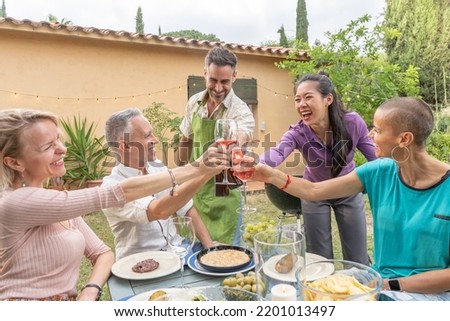 Happy middle aged men and women cheers at country house picnic. Lifestyle concept with cheerful friends having fun together in afternoon relaxing time
