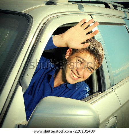 Toned photo of Happy Teenager sitting in the Car and wave Goodbye