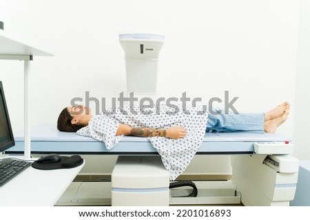 Profile of a sick young woman at the medical lab doing a densitometry scan test to to get a bone diagnosis 