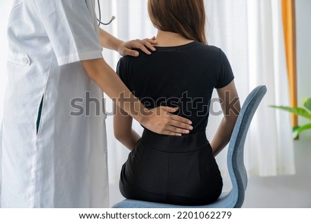Female doctor doing physiotherapy to treat back. Female office worker back pain treatment. Doctor, chiropractor, office syndrome. Royalty-Free Stock Photo #2201062279