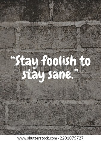 Motivational quote "Stay foolish to stay sane" in wall concrete background