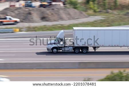 A blank, white semi-truck and trailer is seen on a multi-lane highway on a sunny day. Royalty-Free Stock Photo #2201078481