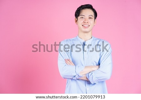 Portrait of young Asian man on pink background
