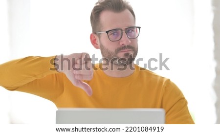 Portrait of Man with Laptop Showing Thumbs Down