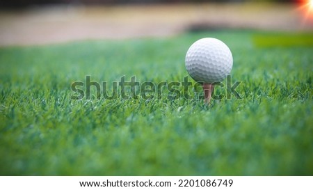 Golf ball close up on tee grass on blurred beautiful landscape of golf background. Concept international sport that rely on precision skills for health relaxation.	