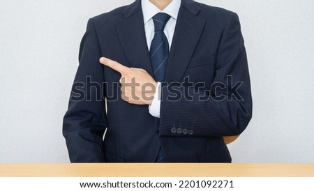 A businessman sitting at a table. Finger point pose.