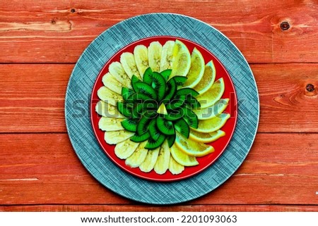 beautifully decorated slices of fresh orange, lemon on a round plate. green kiwi.  Lime. on a wooden background. the concept of the holiday.  Valentine's Day. space for text. Still-life