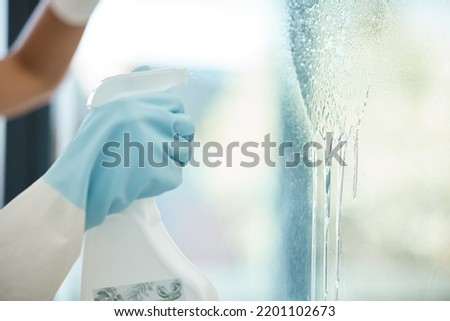 Cleaner hands with spray bottle, liquid and window cleaning in an office, house apartment or modern glass interior. Spring clean or service worker spraying soap water container for career background Royalty-Free Stock Photo #2201102673