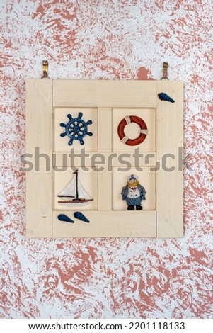 Wooden frame with marine symbols. Rudder, lifebuoy, sailboat and sailor. On a colorful background.