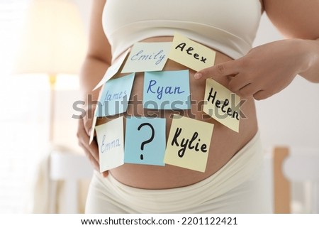 Pregnant woman with different baby names on belly indoors, closeup Royalty-Free Stock Photo #2201122421
