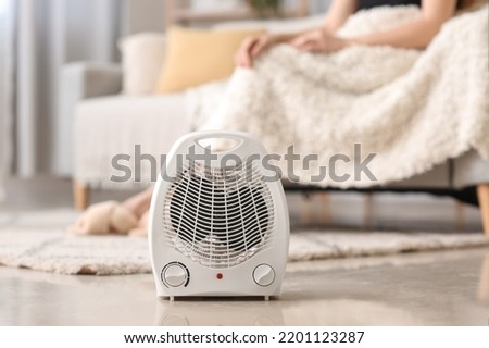 Electric fan heater on floor in living room, closeup Royalty-Free Stock Photo #2201123287