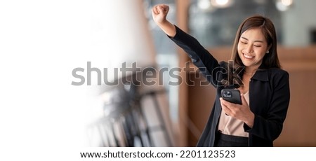 Happy Asian woman holding a smartphone, raise hand up and exciting with good news. Banner background.