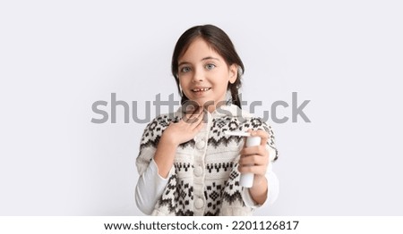 Little girl with medical spray on light background