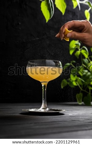 Expressing citrus oils from lemon zest onto a gold rush sour cocktail served in a coupe glass  Royalty-Free Stock Photo #2201129961