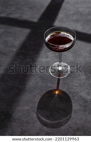 A coupe cocktail glass of red vermouth or liqueur shot with hard back light on grey background Royalty-Free Stock Photo #2201129963