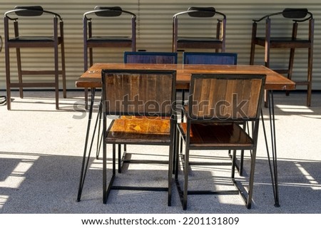 Wooden chairs at a closed restaurant are set up outside the shop in the morning sun.