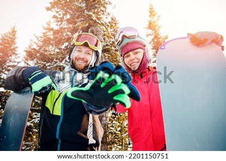 Concept friends travel love winter sport. Happy couple man and woman snowboarders background sunset ski resort.