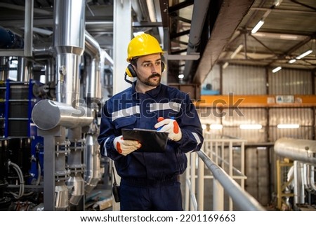 Night shift worker foreman walking through heating plant and controlling process of heating. Royalty-Free Stock Photo #2201169663