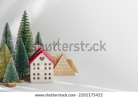 Miniature houses and fir trees on white background. Winter cute landscape. Cozy small world. Christmas decorations, holiday concept. 
