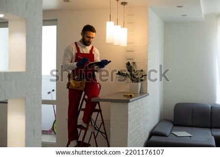 Electrician worker installation electric lamps light inside apartment. Construction decoration concept. Royalty-Free Stock Photo #2201176107