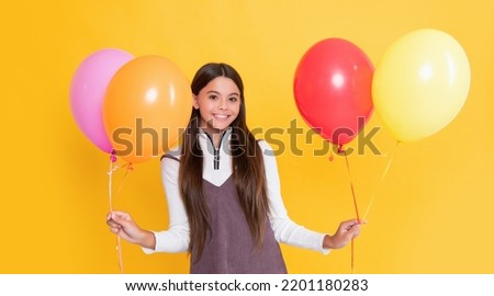 positive child with party colorful balloons on yellow background