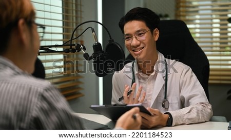 Friendly doctor in white coat and stethoscope making medication advise via online podcast, online medical blog from home