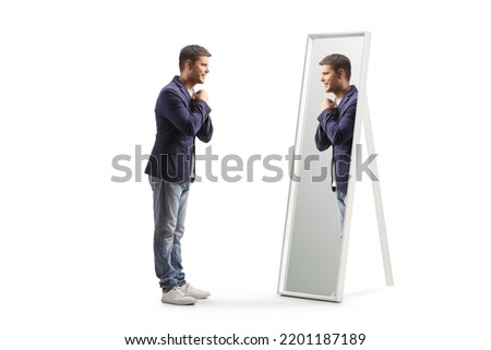 Full length profile shot of a young man getting ready and looking at a mirror isolated on white background Royalty-Free Stock Photo #2201187189