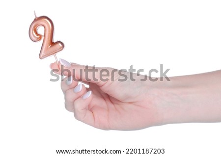 Candle with number 2 in hand on white background isolation