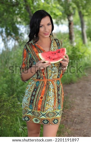 Pretty woman is wearing dress eating watermelon