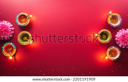 Happy Diwali - Clay Diya lamps lit during Diwali, Hindu festival of lights celebration. Colorful traditional oil lamp diya on red background Royalty-Free Stock Photo #2201191909