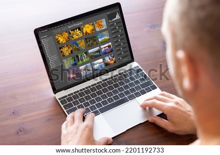 Man editing photo files on laptop computer