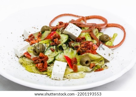 Salad with feta cheese, sun-dried tomatoes, pickled onions with balsamic sauce on a white plate. horizontal photo