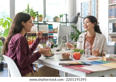 Women having a lunch break together in the office, they are eating salad and talking to each other Royalty-Free Stock Photo #2201195395